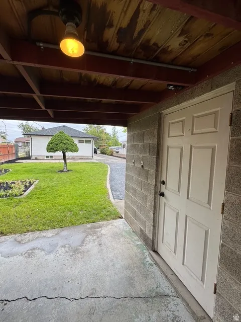 Covered concrete patio with overhead lighting and a paneled entry door