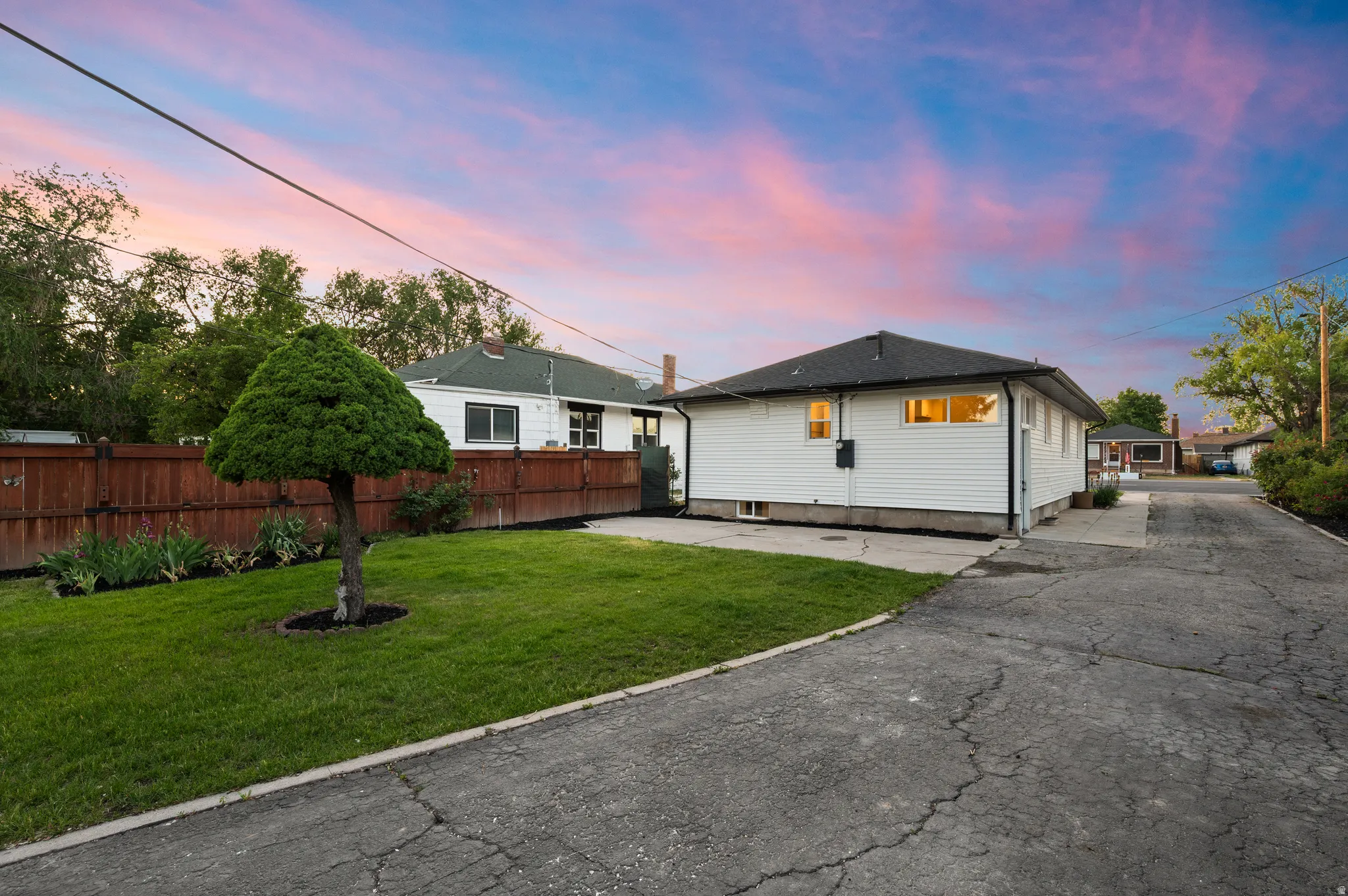 Exterior featuring white siding, a dark shingle roof, and a privacy fence