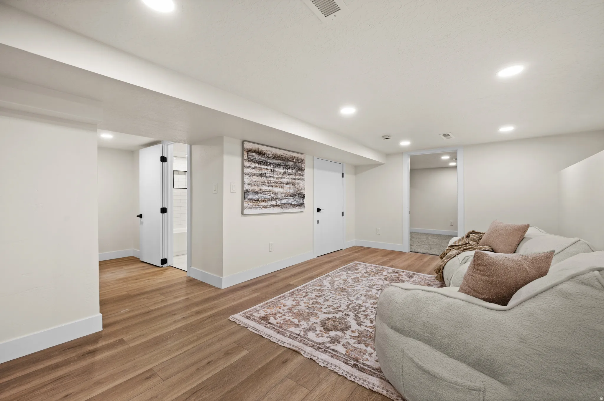 Spacious interior with wood-finish flooring, white baseboards, and recessed lighting