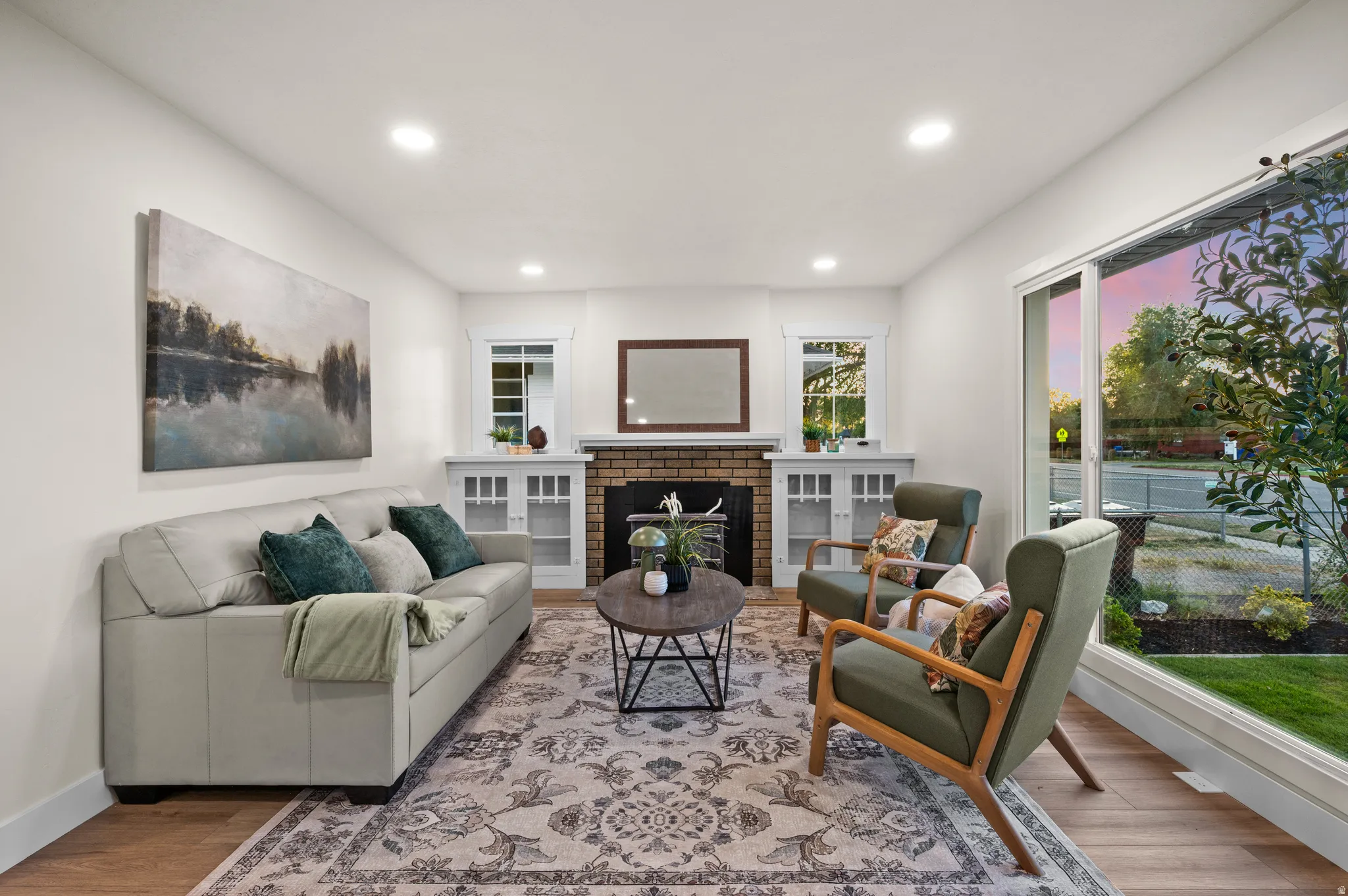 Living area featuring wood-finish flooring, recessed lighting, and a brick fireplace