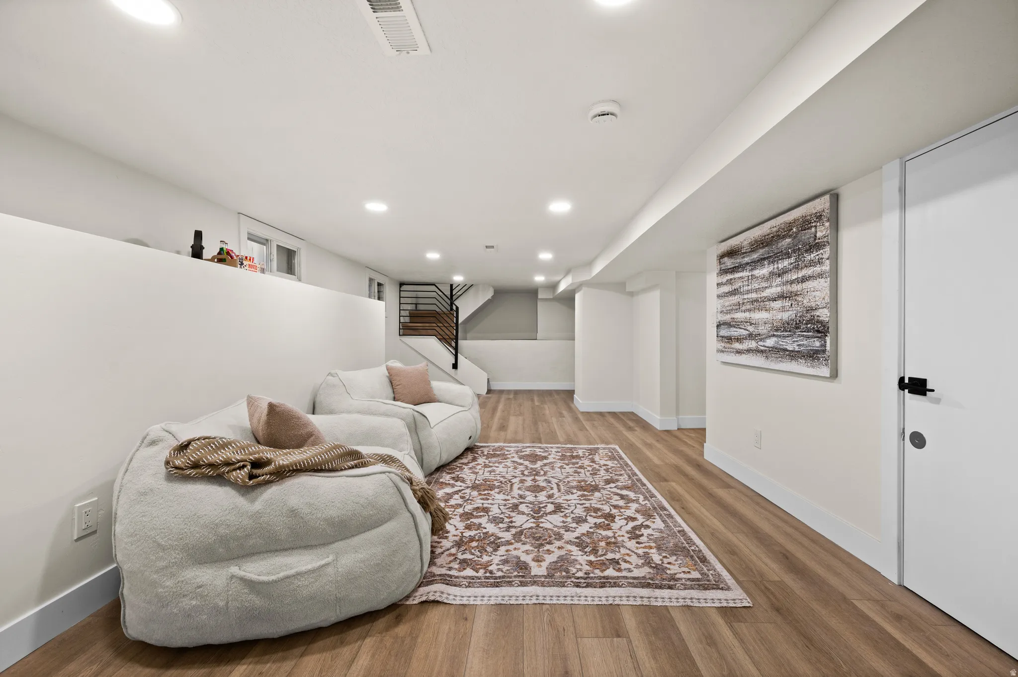 Finished lower level with wood-finish flooring, recessed lighting, and white baseboards