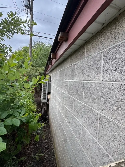 Exterior concrete block wall with a red-painted fascia and exposed rafter tails