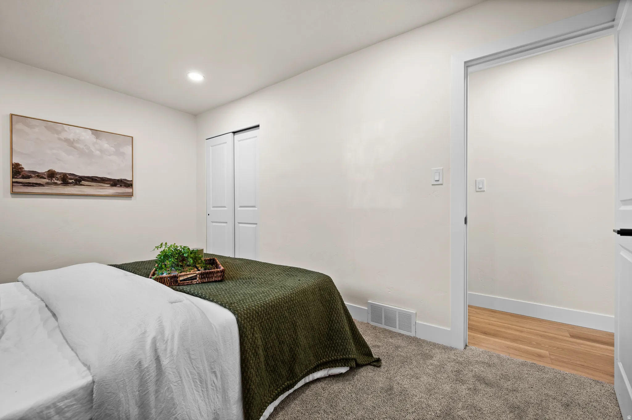 Carpeted bedroom featuring a built-in sliding door closet, recessed lighting, and a white baseboard trim