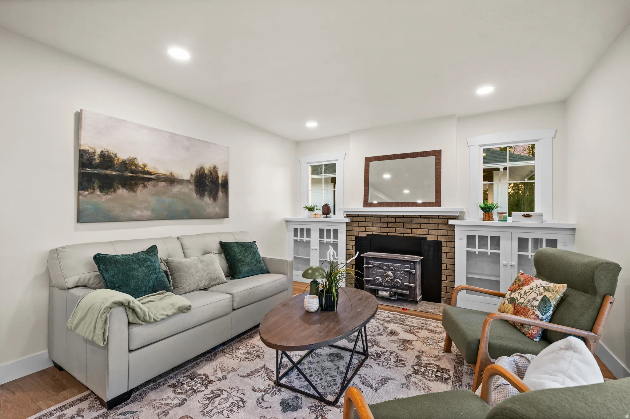 Living room featuring a brick fireplace with an ornate wood-burning stove insert, flanked by built-in cabinetry with glass-front doors