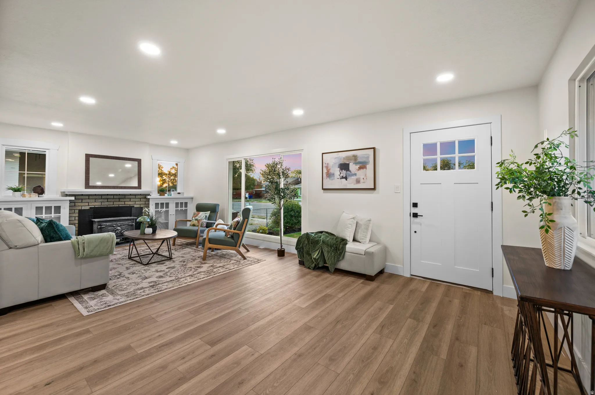 Open concept living area featuring wood-finish flooring, recessed lighting, and a fireplace with brick surround