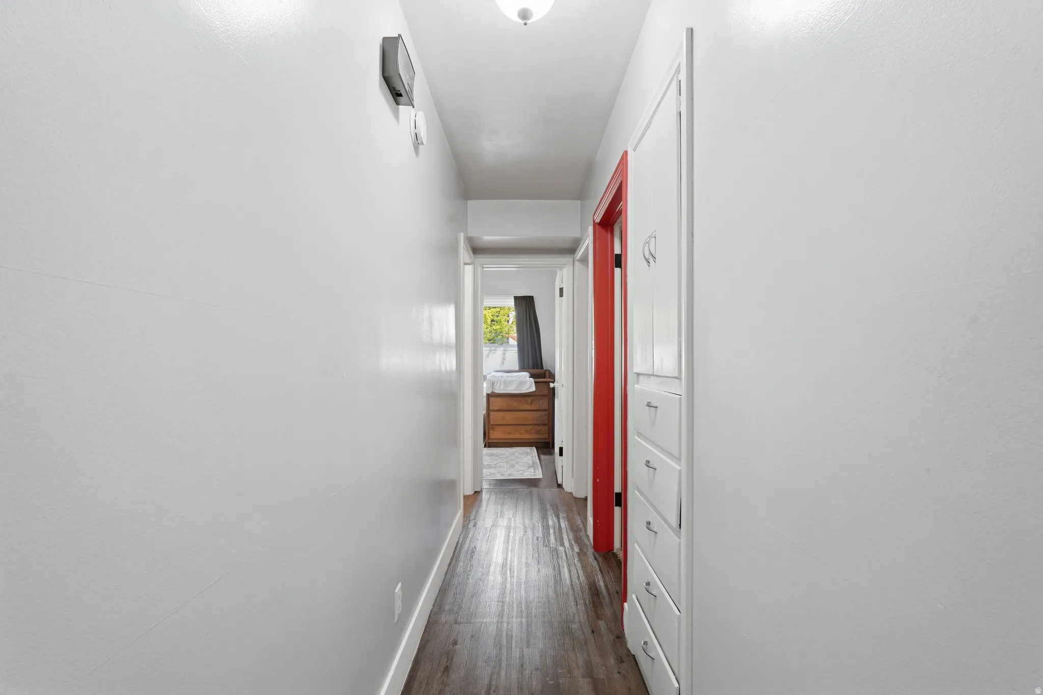Hallway featuring wood-finish flooring and light-toned walls