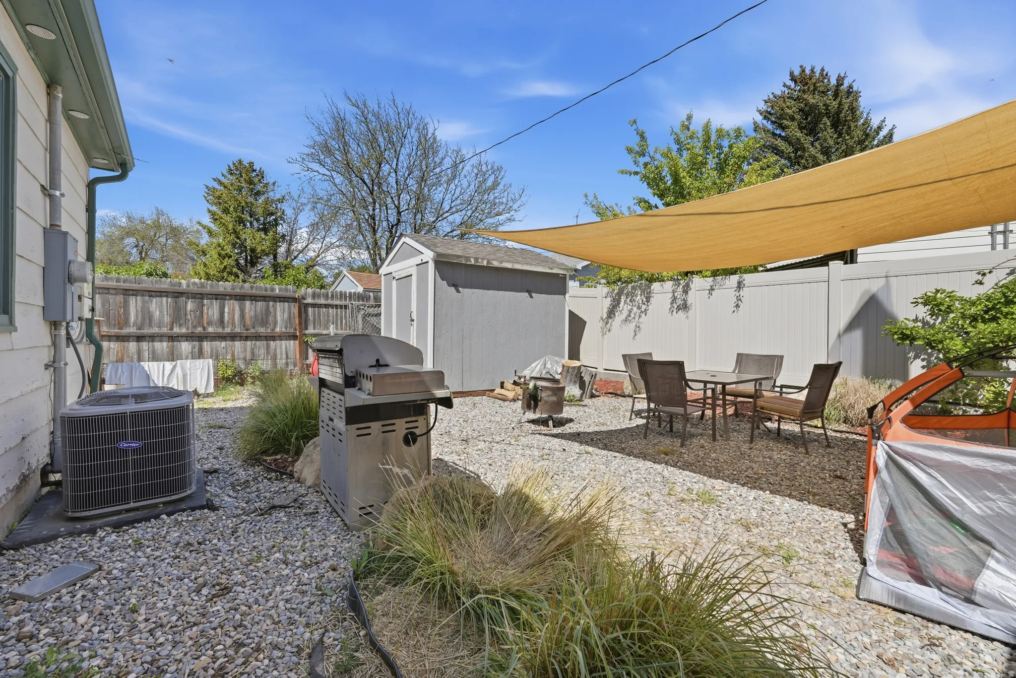 Private backyard featuring a gravel patio, mature landscaping, and a storage shed