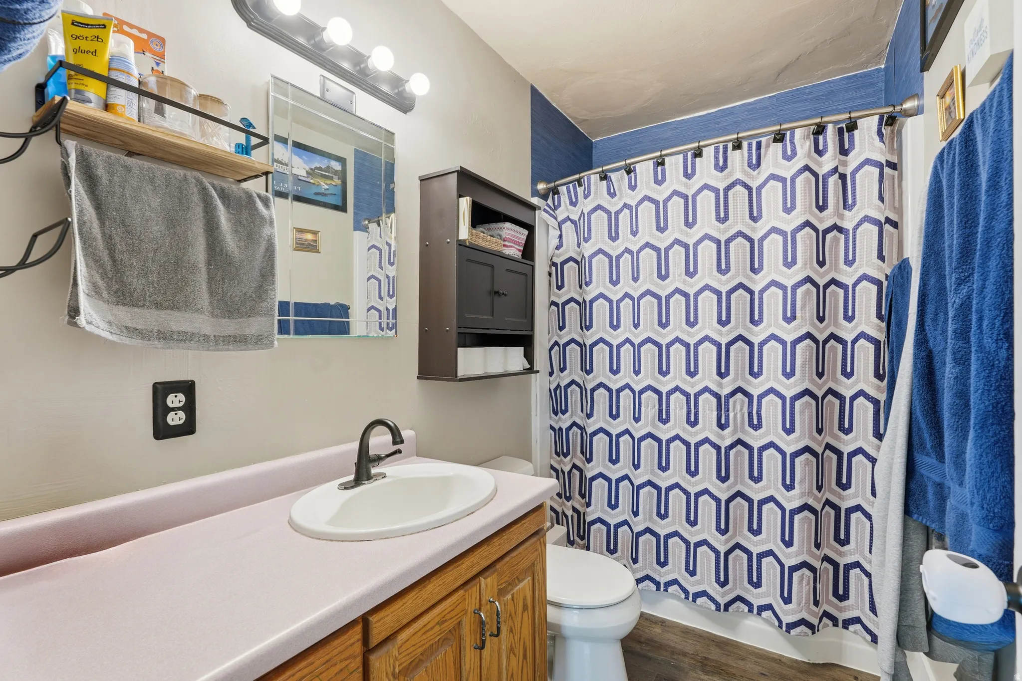 Bathroom featuring a single vanity with wood cabinetry, a pink countertop, and a white oval sink