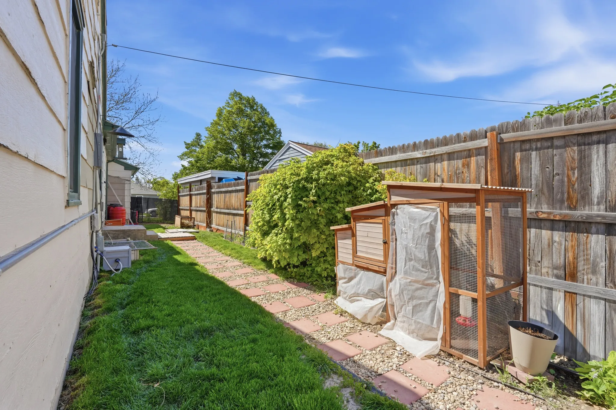 Side yard with a stone paver pathway, manicured lawn, and wood privacy fencing