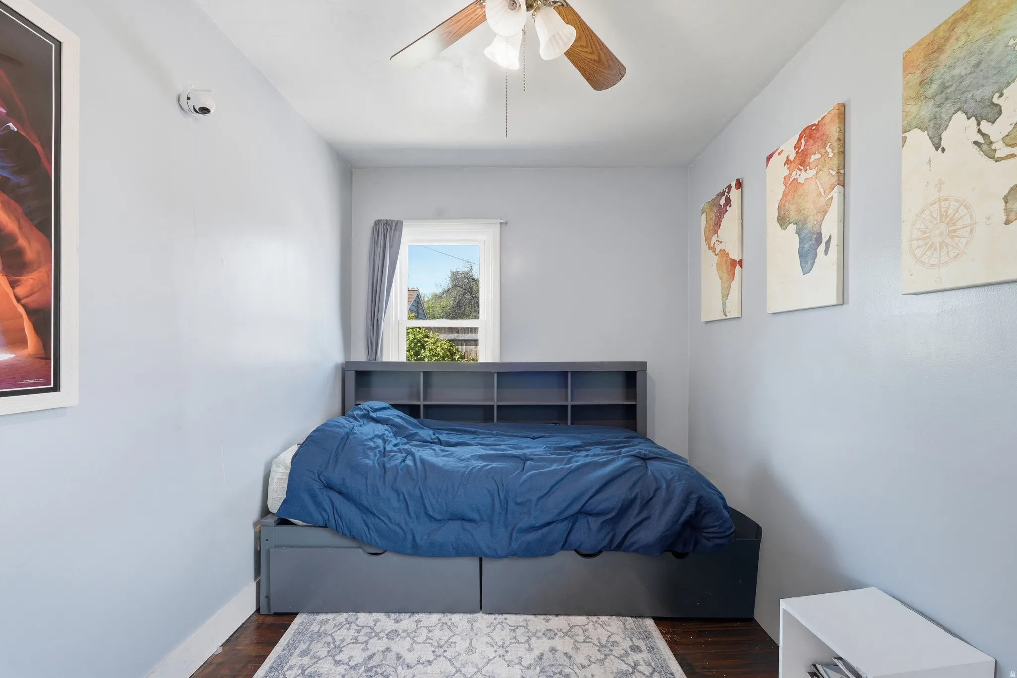 Room featuring a ceiling fan with light fixture, hardwood flooring, and a single window with curtain rod
