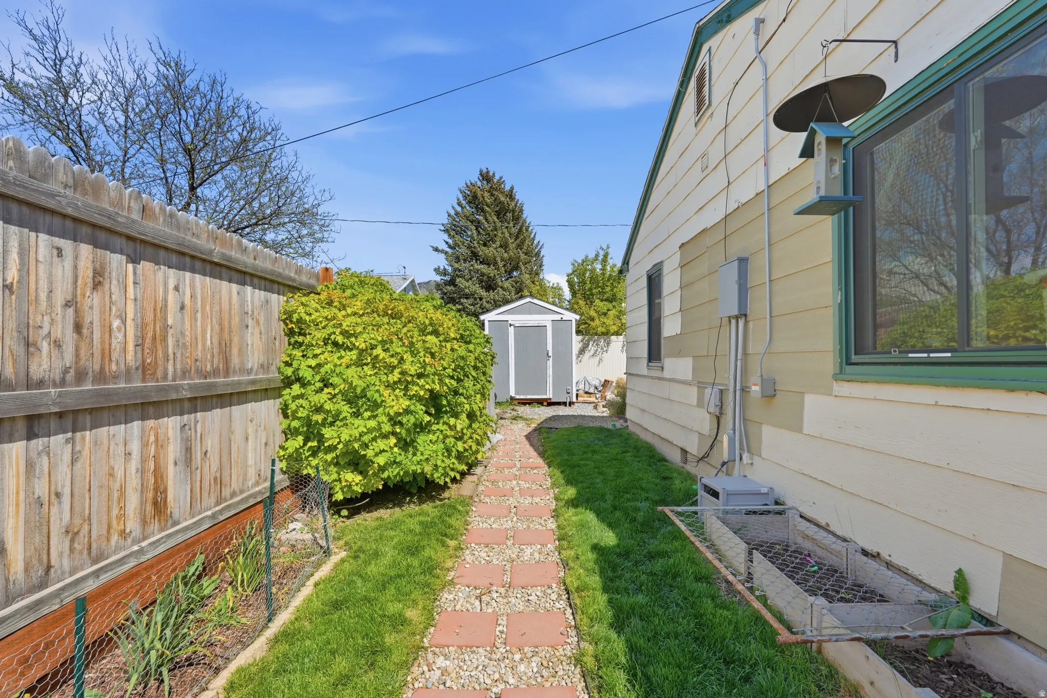 Side yard featuring a brick paver pathway, manicured lawn, and privacy fencing