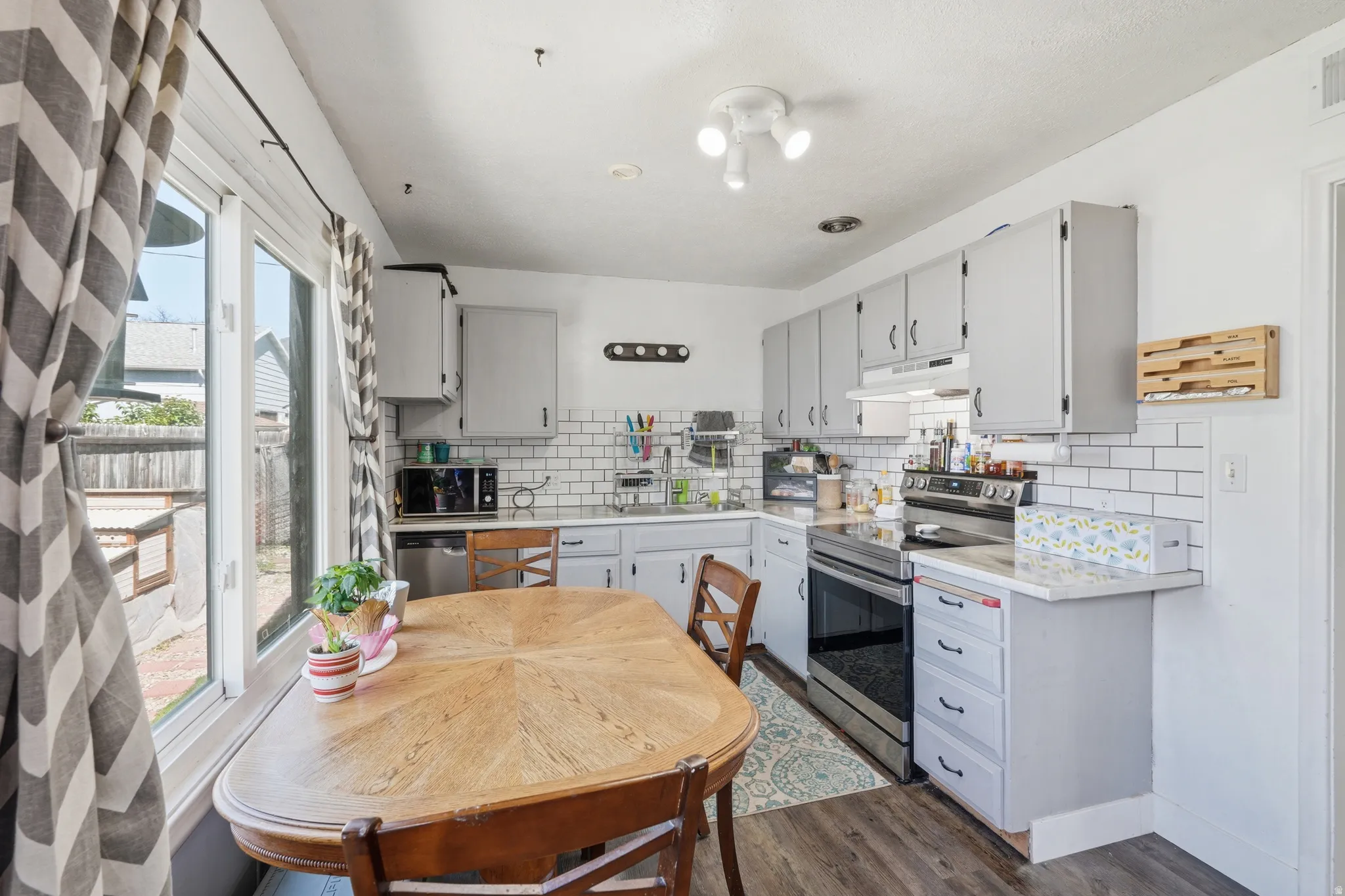 Kitchen featuring wood-finish flooring, white subway tile backsplash, white countertops, and light gray cabinetry