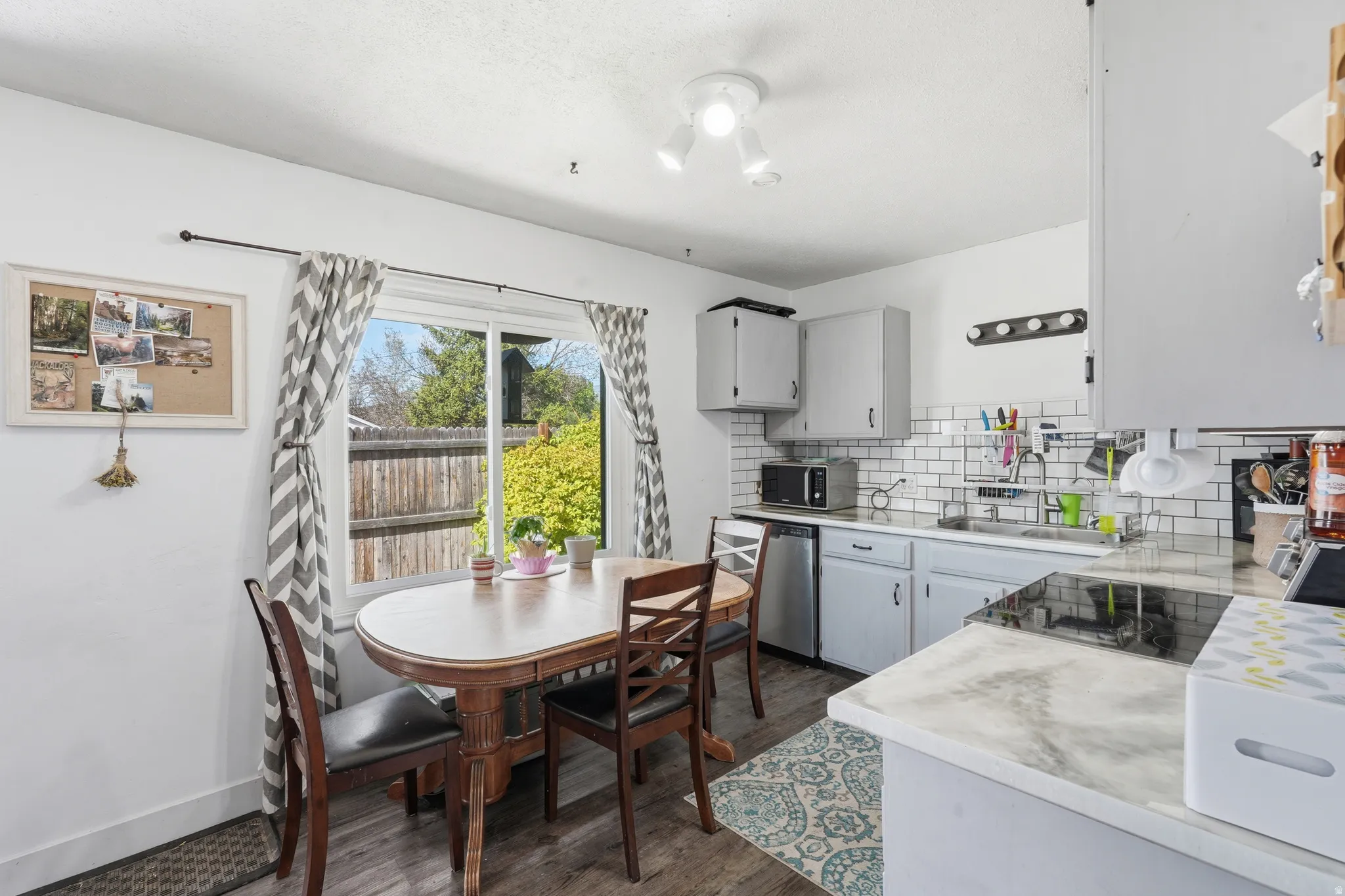 Kitchen area featuring a window, light gray cabinetry, subway tile backsplash, wood-finish flooring, and white countertops