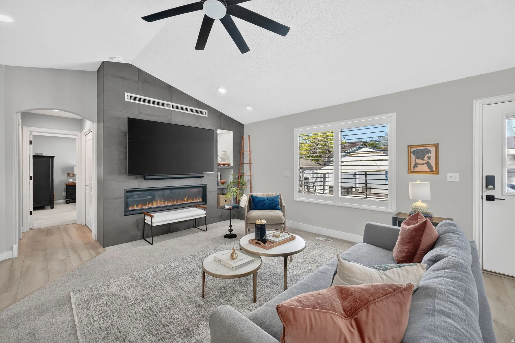 Vaulted living room with a contemporary fireplace feature wall, light wood-finish flooring, and recessed lighting