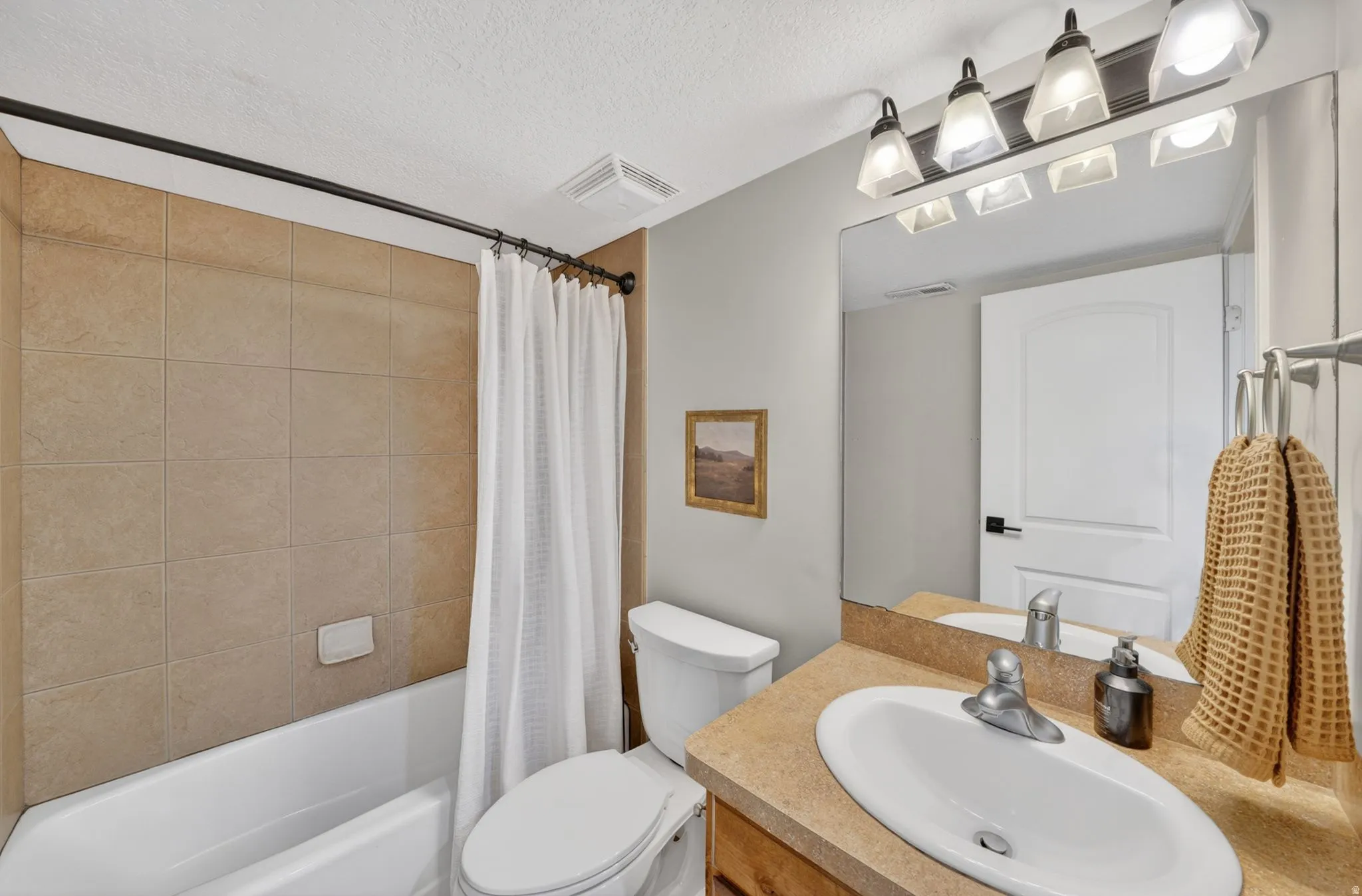 Bathroom featuring a vanity with an integrated sink, a rectangular mirror, and a four-light fixture