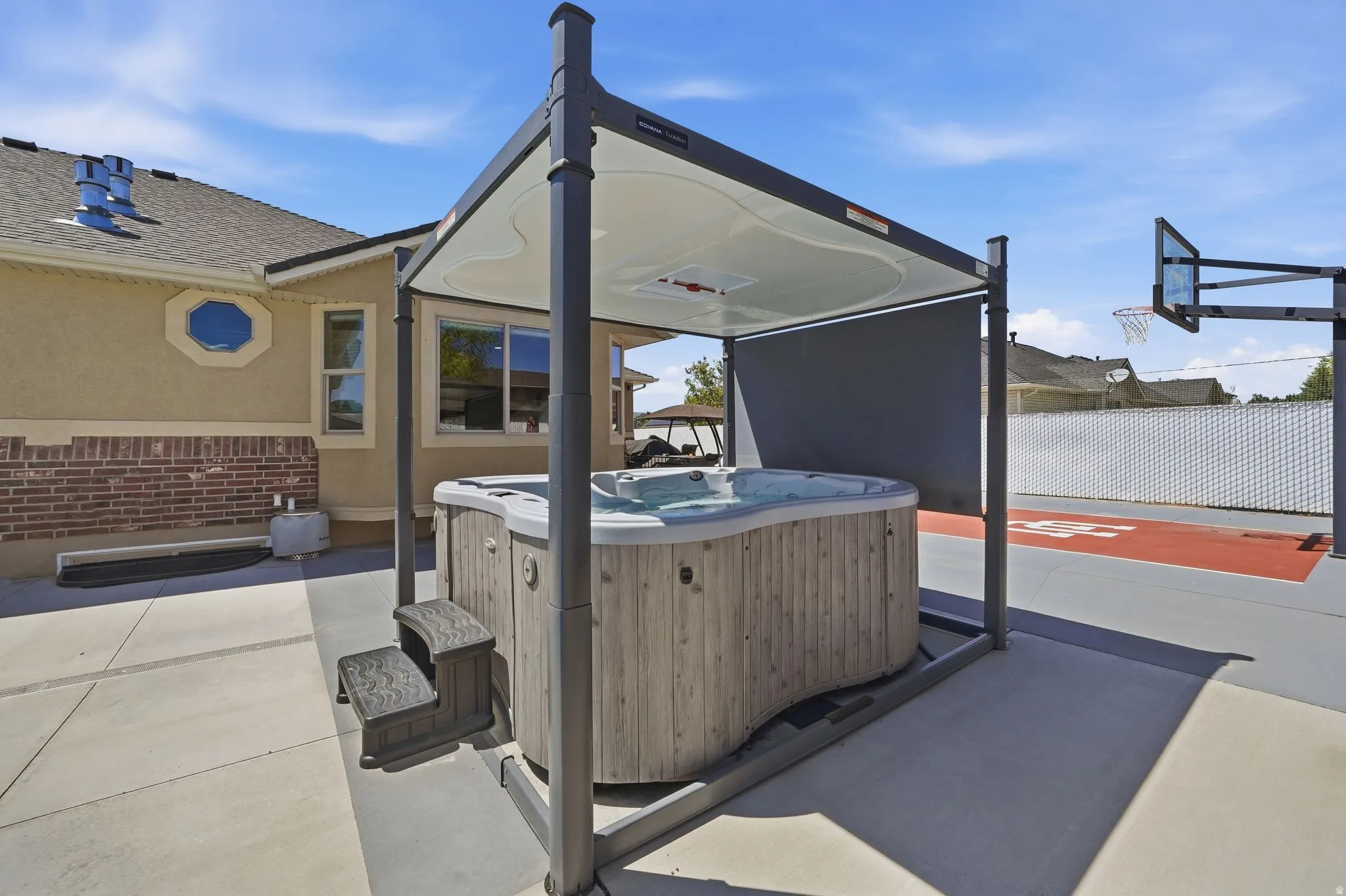 Outdoor spa with a protective pergola, positioned on a concrete patio