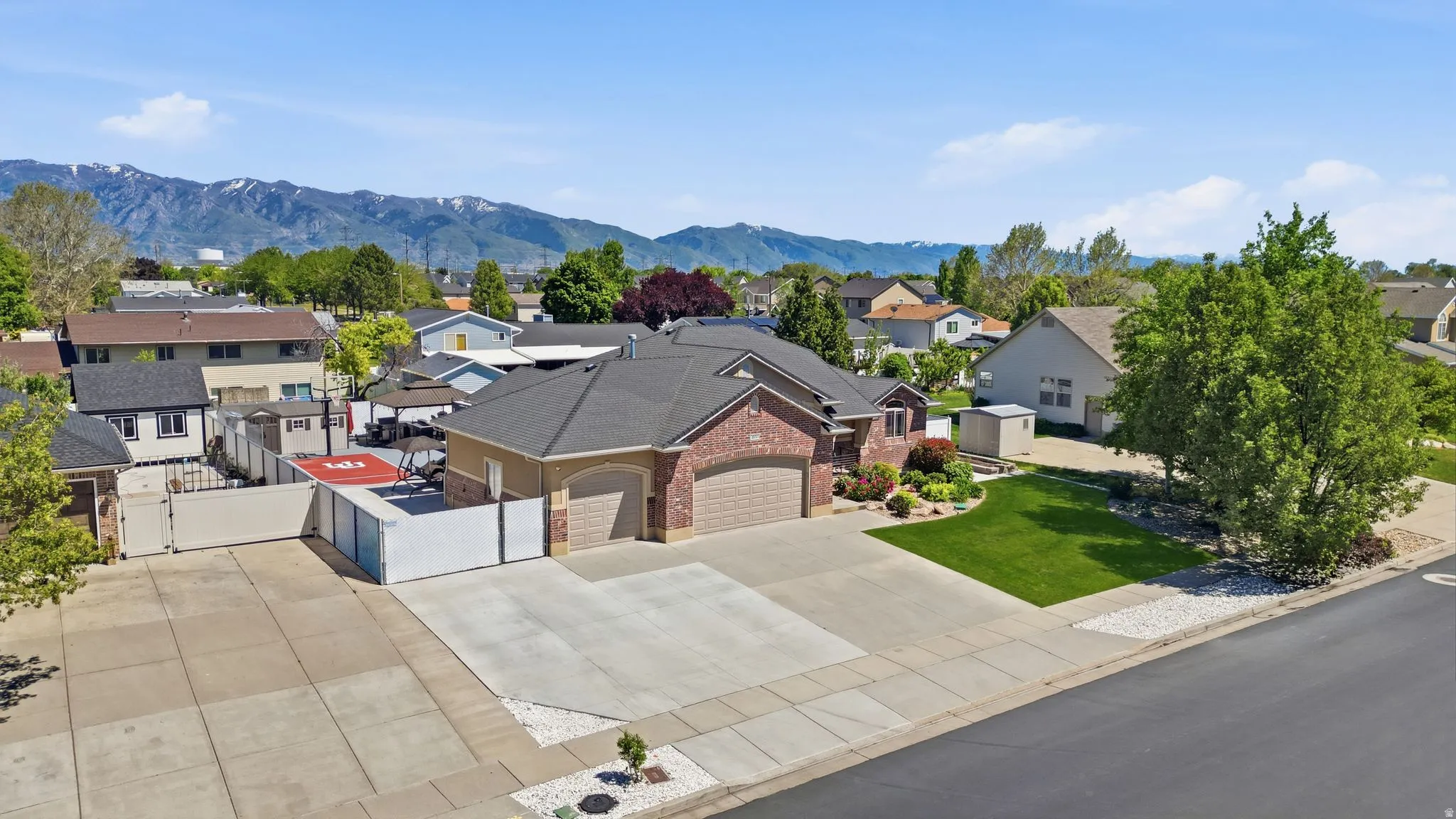 Brick exterior with a multi-car driveway, attached garage, and mature landscaping