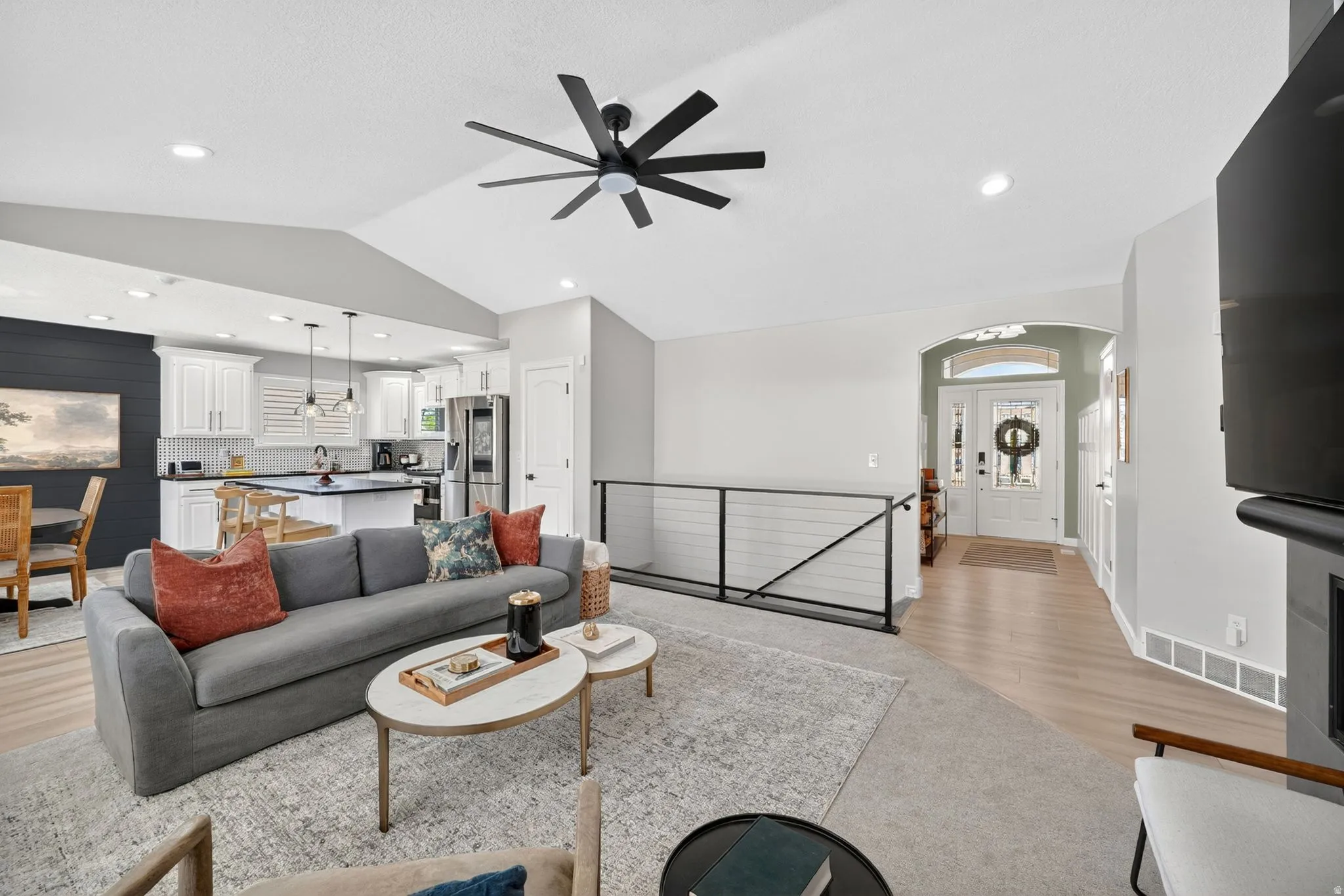 Open-concept living area featuring a vaulted ceiling with a contemporary ceiling fan, recessed lighting, and light wood-finish flooring