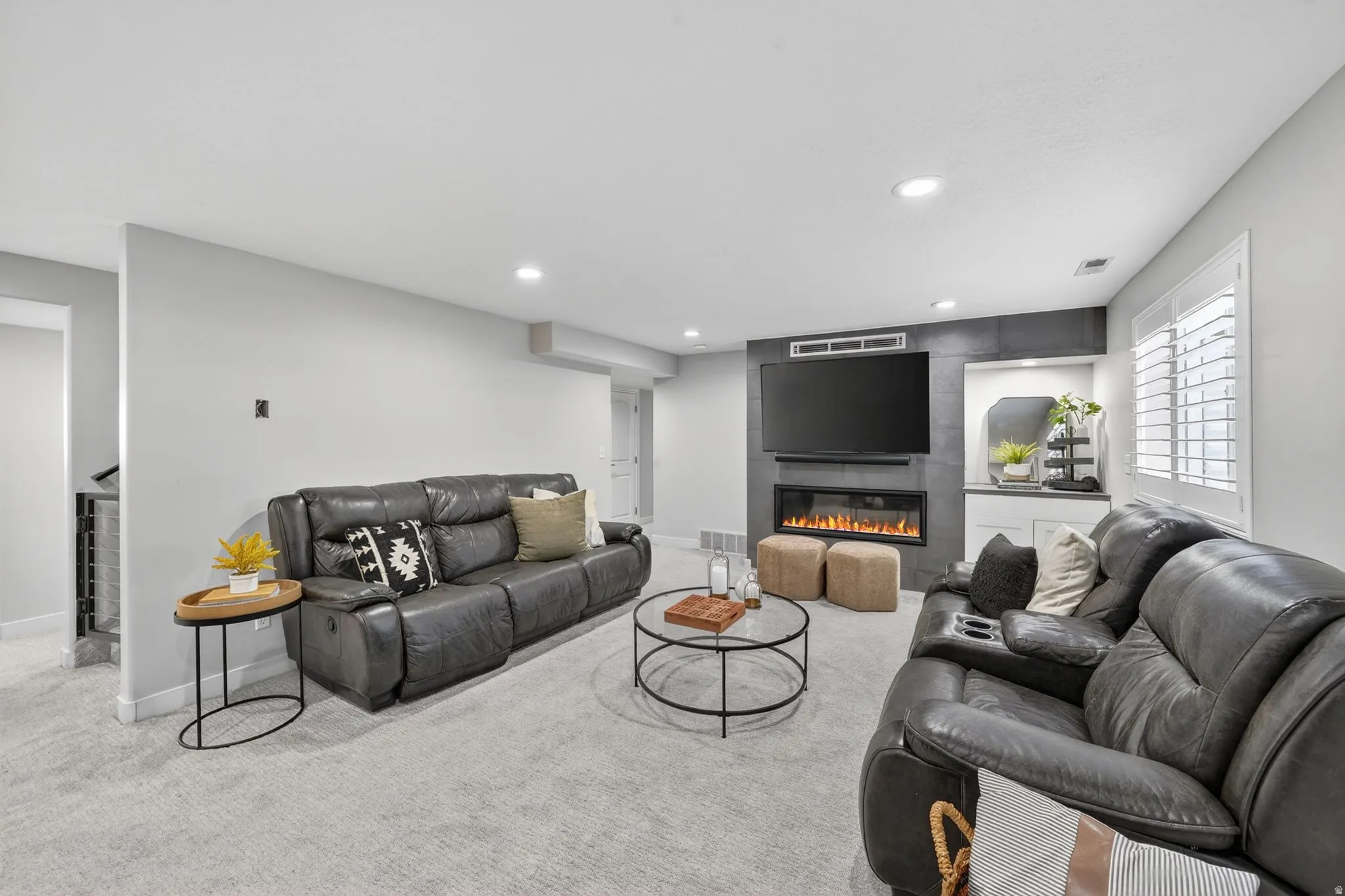 Spacious living area featuring light gray carpet, recessed lighting, and a modern entertainment wall