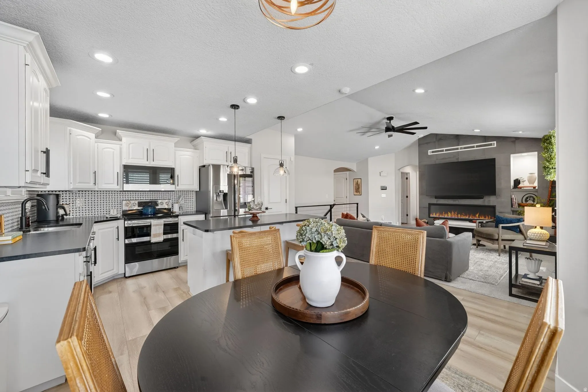 Open-concept living space featuring a modern kitchen with white cabinetry, stainless steel appliances, and a tiled backsplash