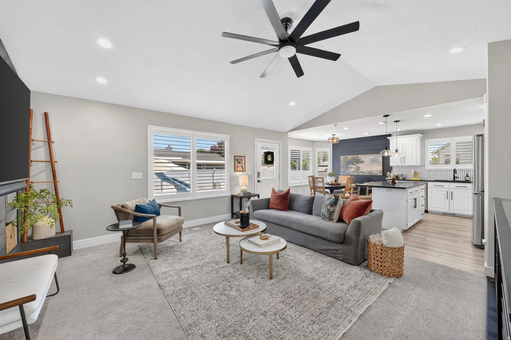 Spacious open-concept living area featuring vaulted ceilings, recessed lighting, and a modern ceiling fan