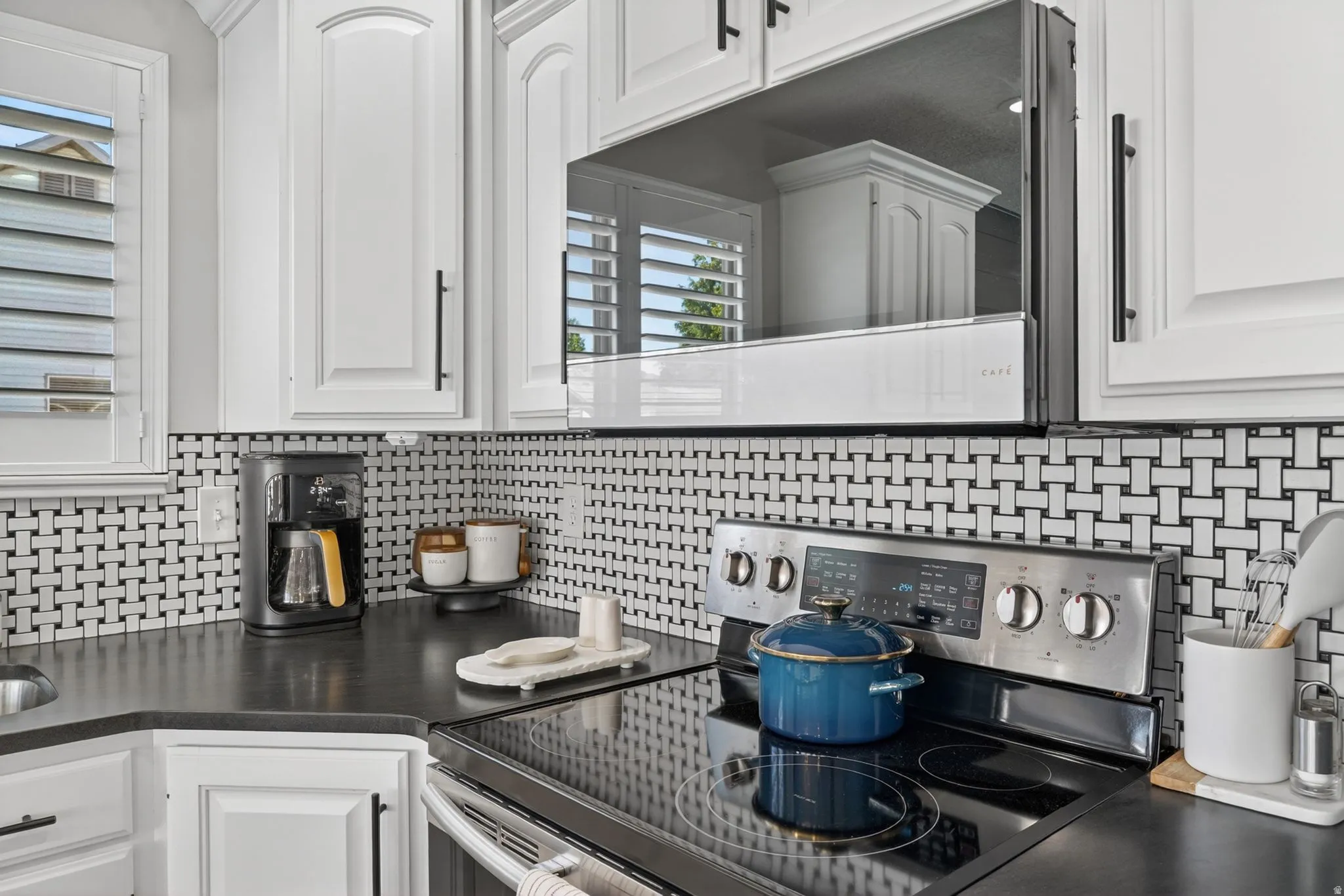 Modern kitchen featuring white cabinetry with black hardware, an over-the-range microwave, and a stainless steel electric range