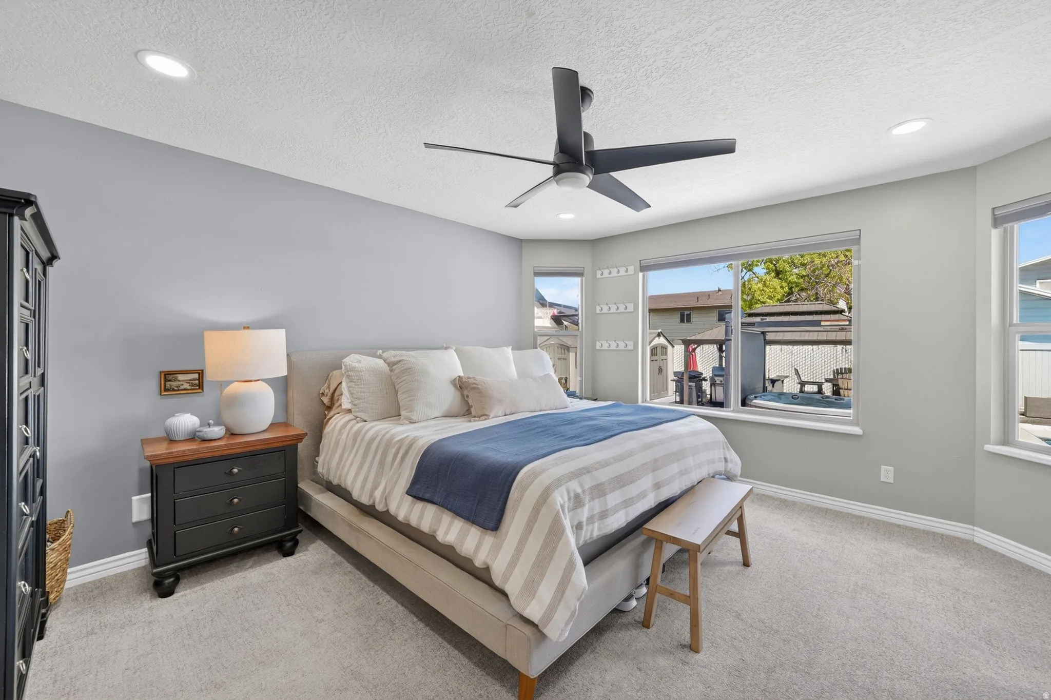 Spacious bedroom featuring light gray walls, recessed lighting, and a modern ceiling fan
