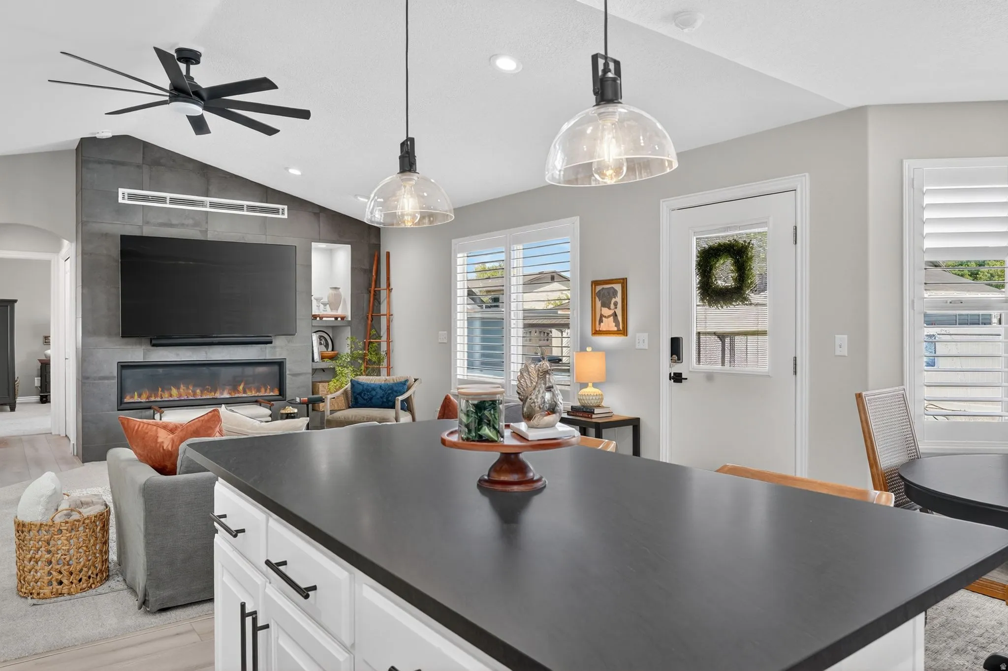 Kitchen island with a dark countertop and white cabinetry, featuring two glass pendant lights