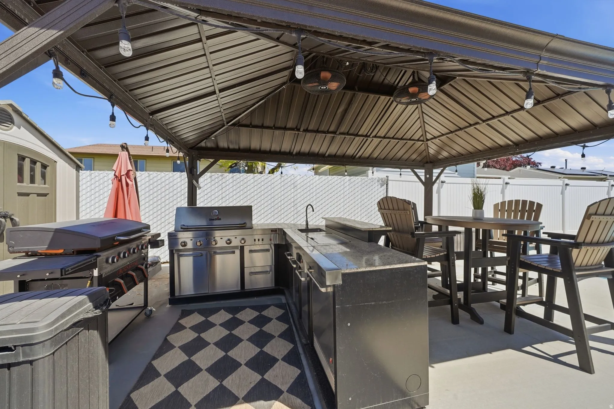 Outdoor covered patio featuring a built-in stainless steel grill, integrated countertop space, and sink
