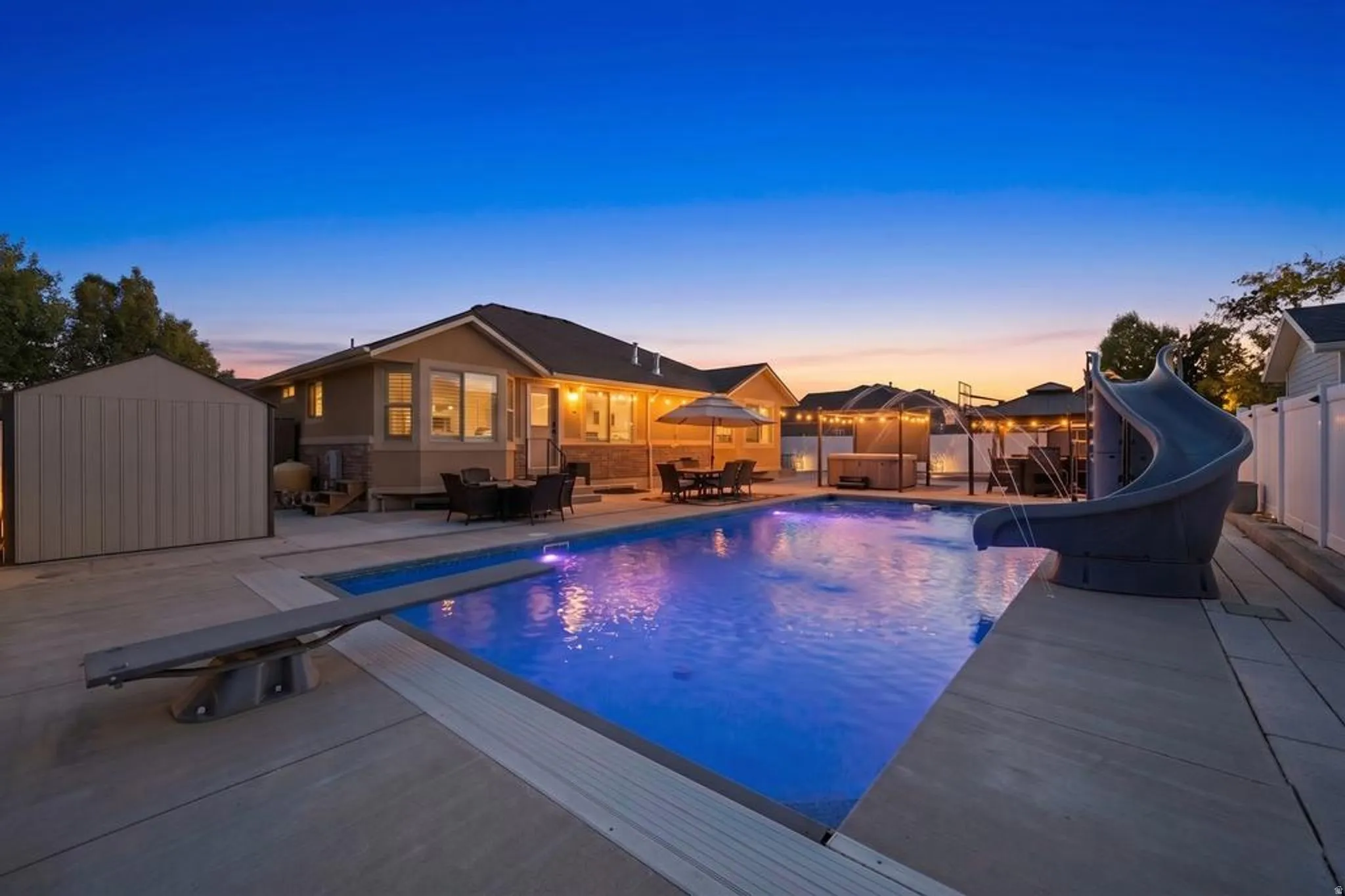 Expansive outdoor area featuring a swimming pool with a diving board and slide, a hot tub, multiple gazebos, and a patio with outdoor dining furniture