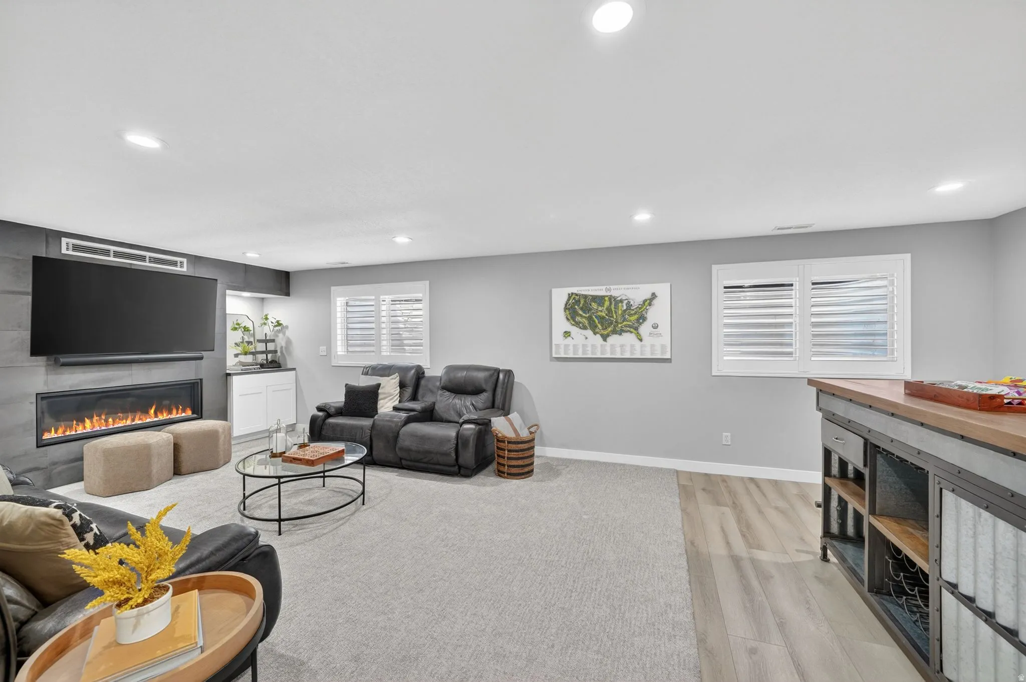 Entertainment space featuring a linear electric fireplace with a dark stone-look surround, a built-in wet bar with white cabinetry, and recessed lighting