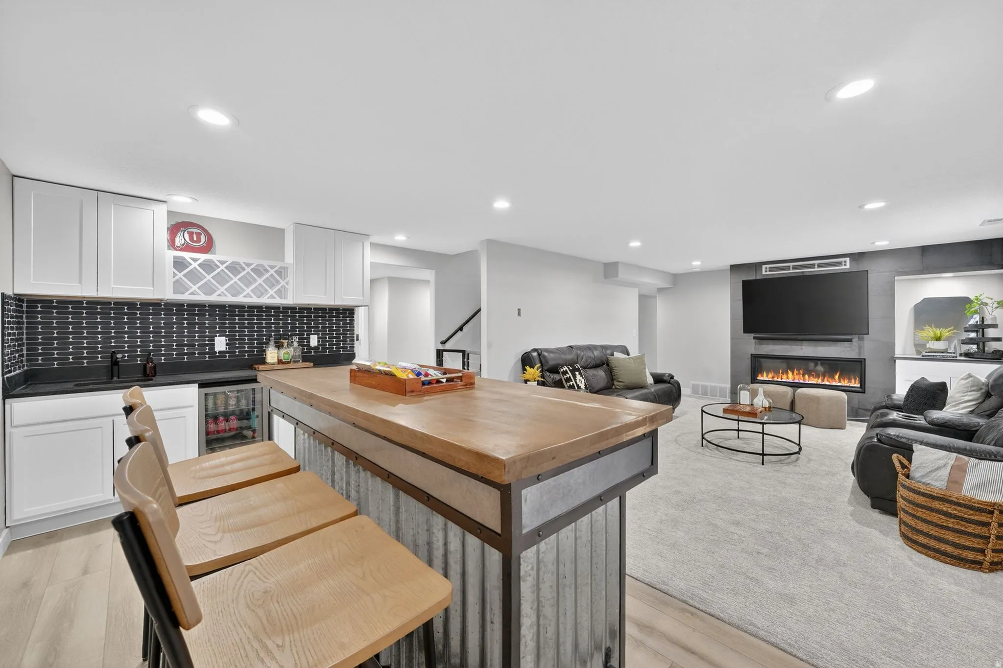 Recreation room featuring a built-in wet bar, wood-finish flooring, recessed lighting, and a modern fireplace