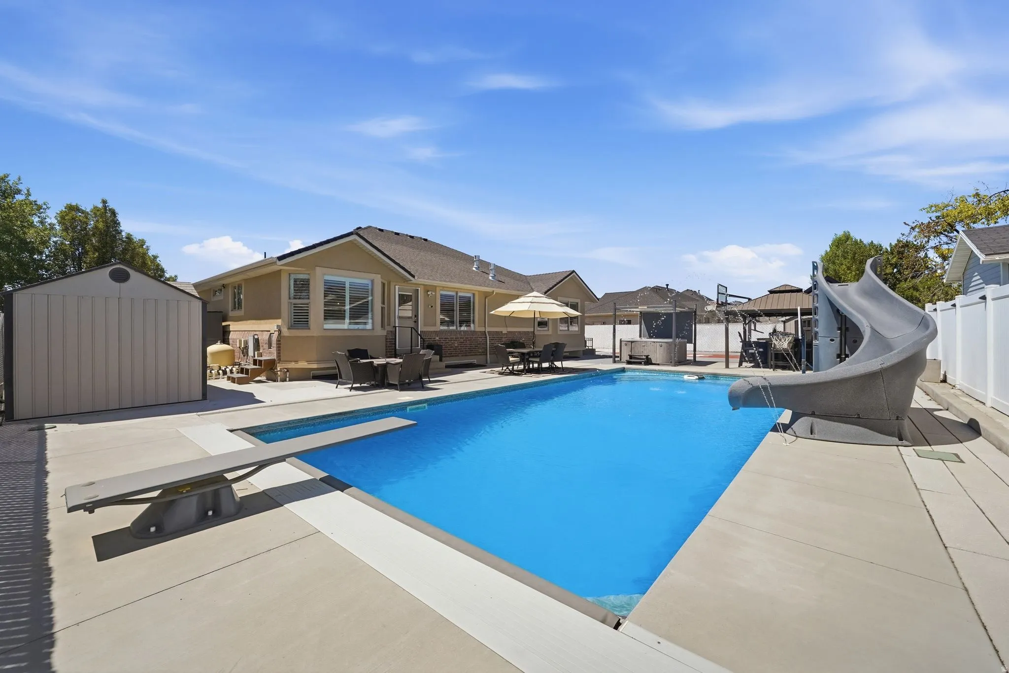 Expansive backyard featuring a rectangular in-ground pool with a diving board and slide
