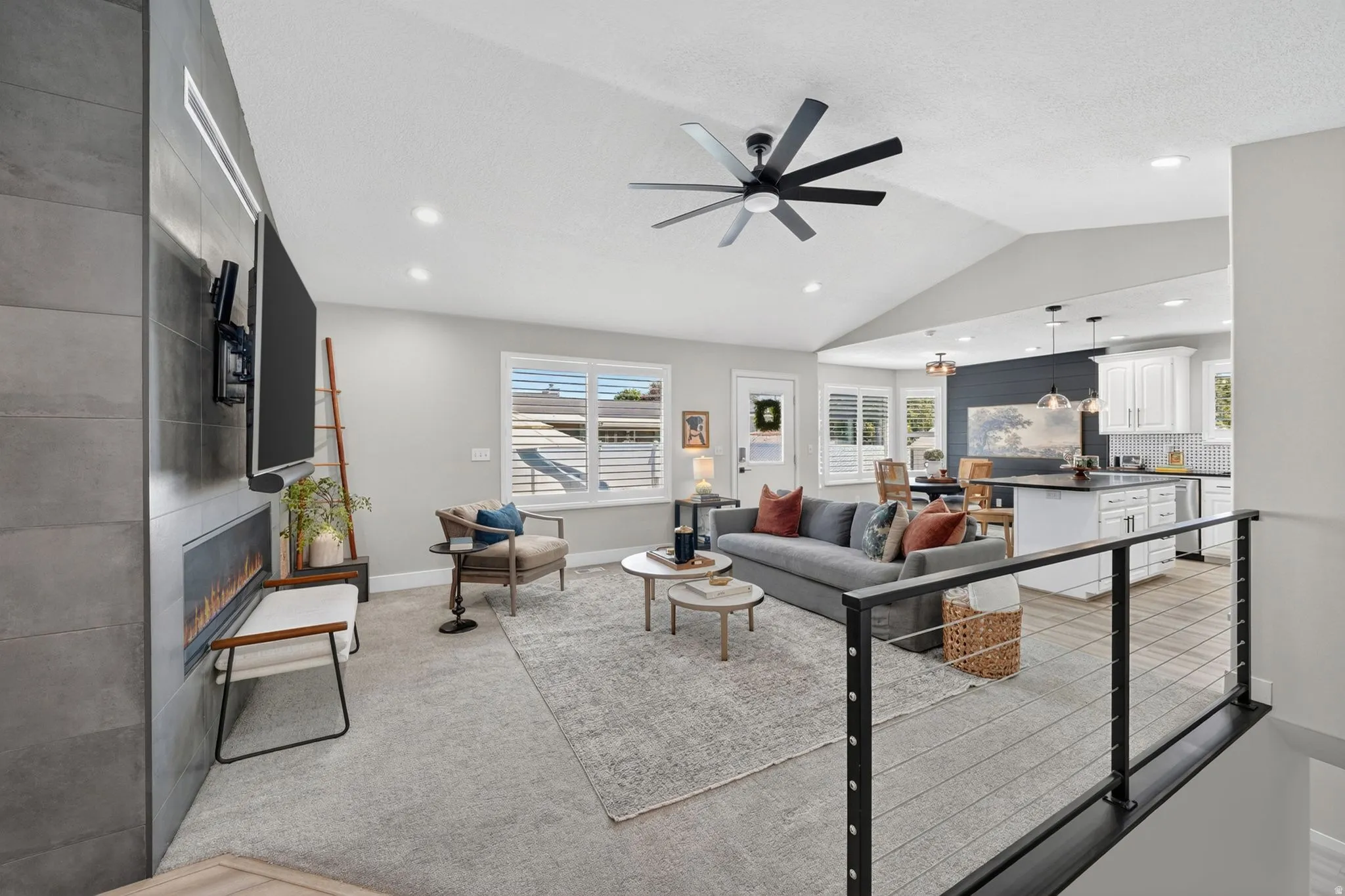 Spacious living area featuring a vaulted ceiling with an overhead fan, recessed lighting, and light-colored carpeting