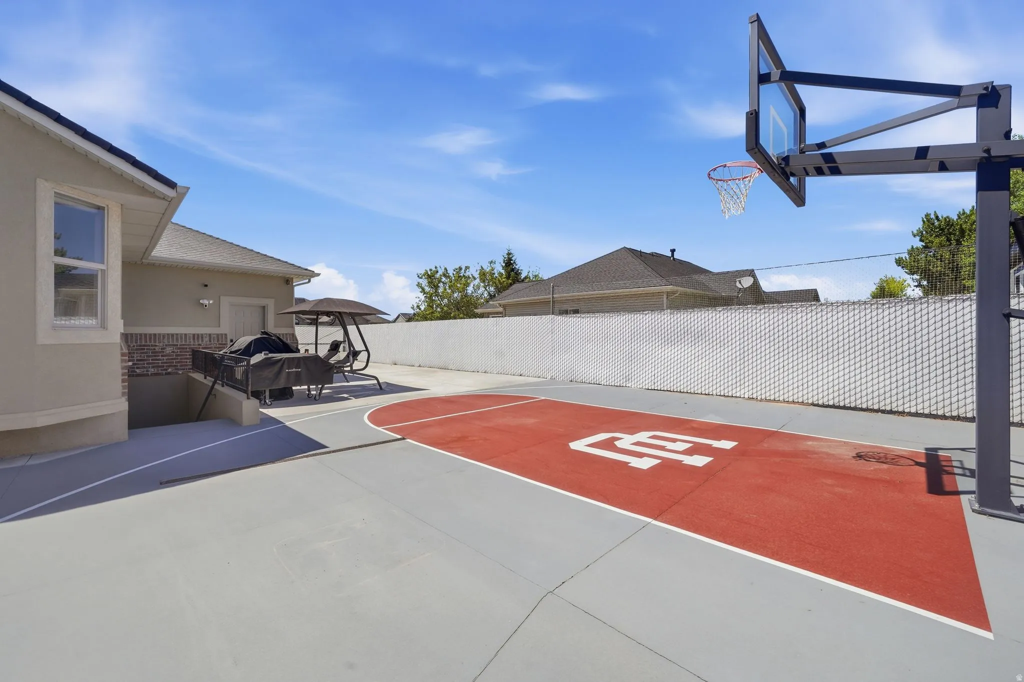Outdoor sport court with a red playing surface and perimeter fencing