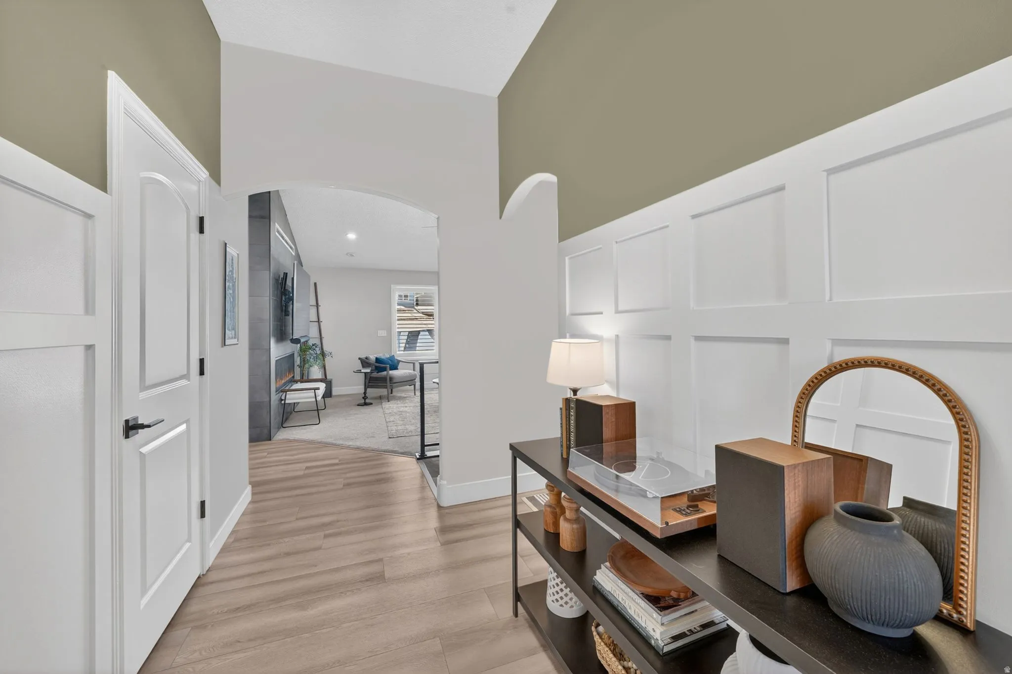 Entryway featuring wood-finish flooring, white wainscoting, and an arched doorway