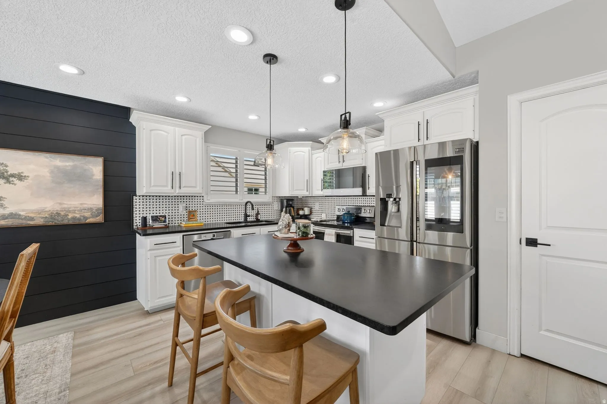 Kitchen featuring white cabinetry, black countertops, and stainless steel appliances