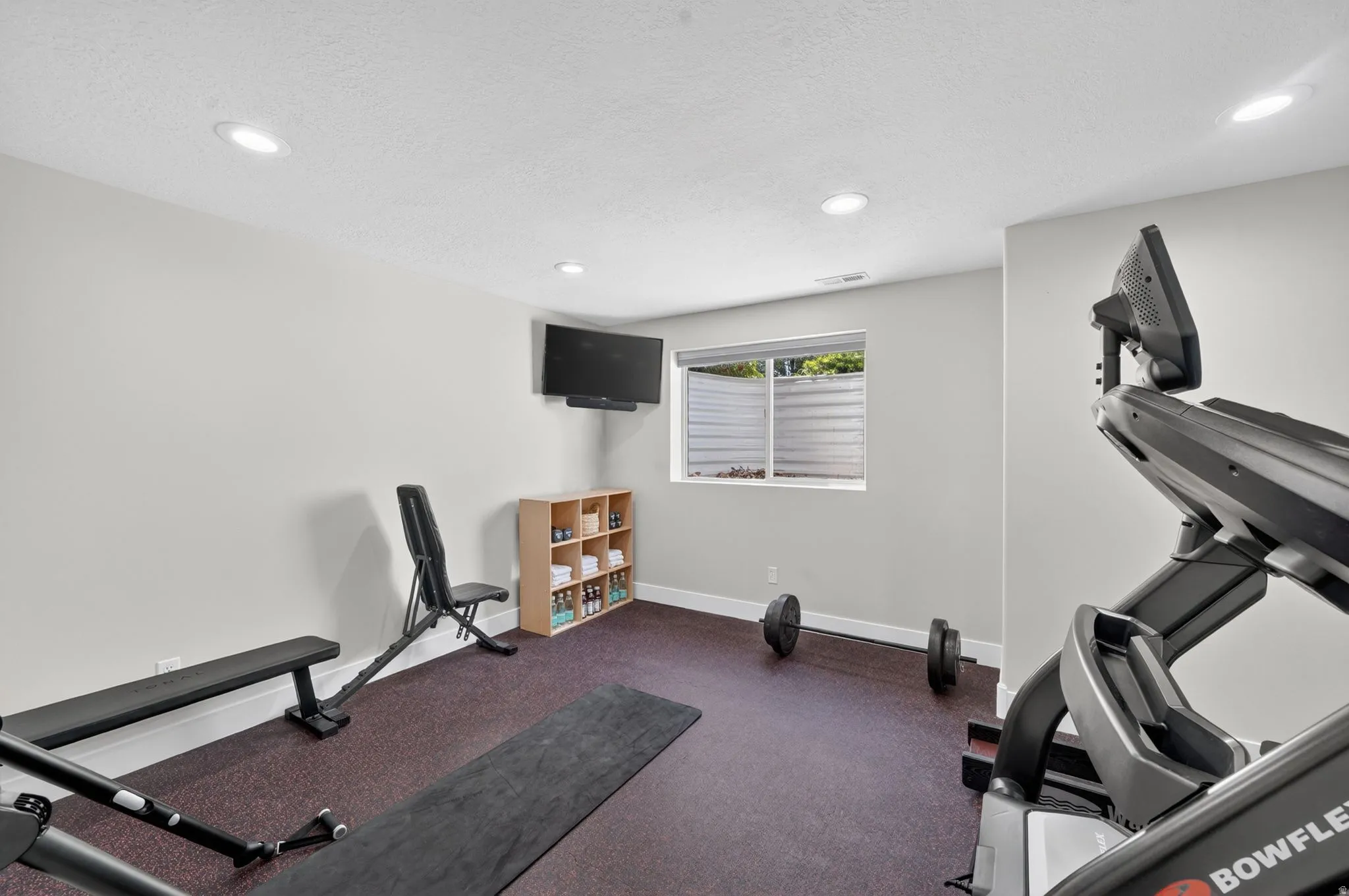 Dedicated fitness area featuring durable rubber flooring and recessed lighting
