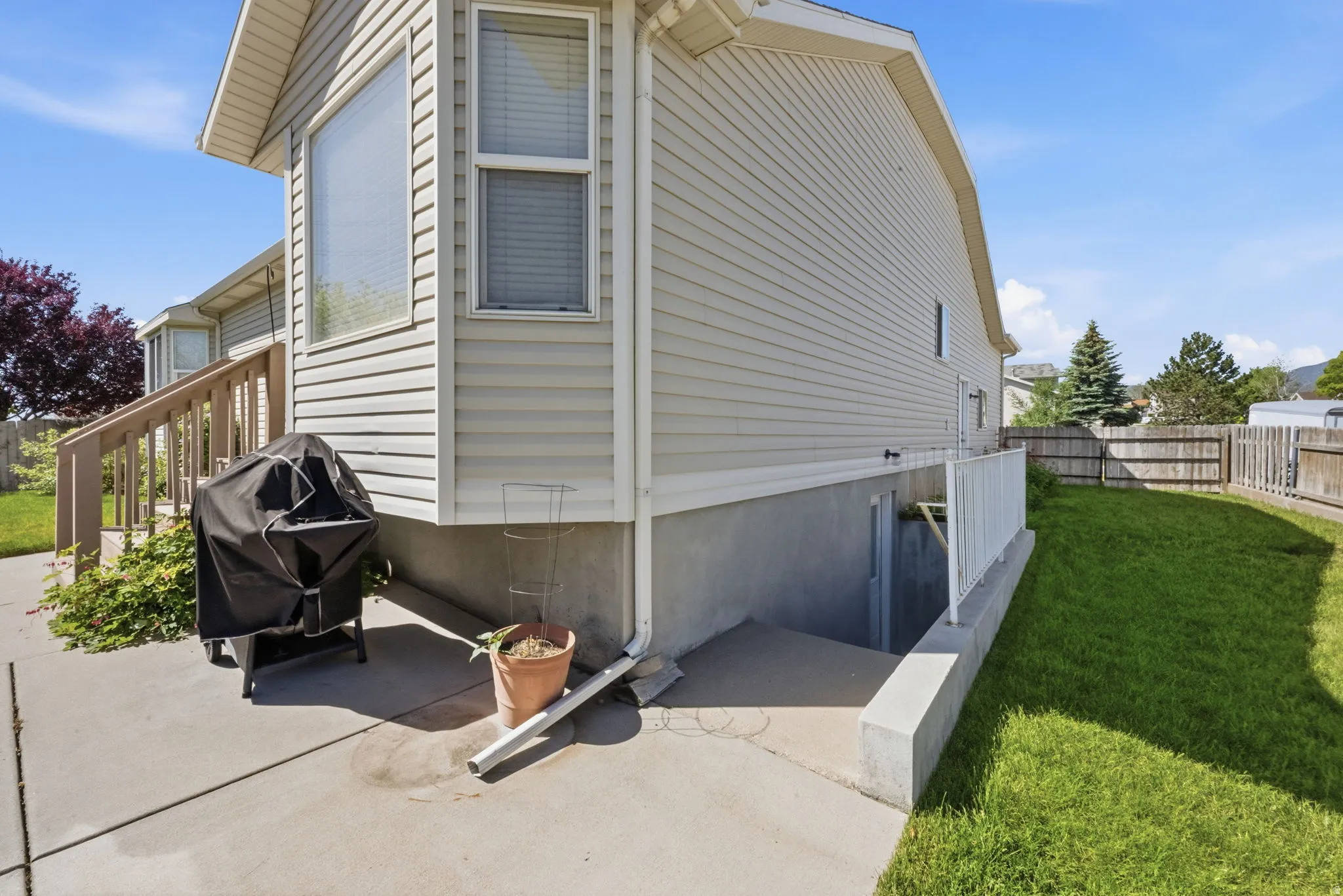 Exterior featuring light-colored siding, a bay window with blinds, and a concrete patio