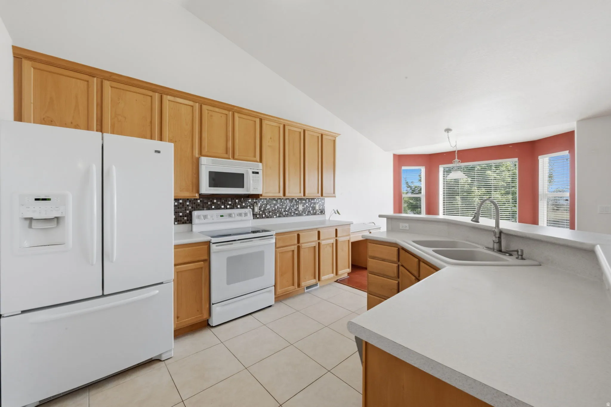 Kitchen featuring light wood cabinetry, white countertops, tile flooring, and a mosaic tile backsplash
