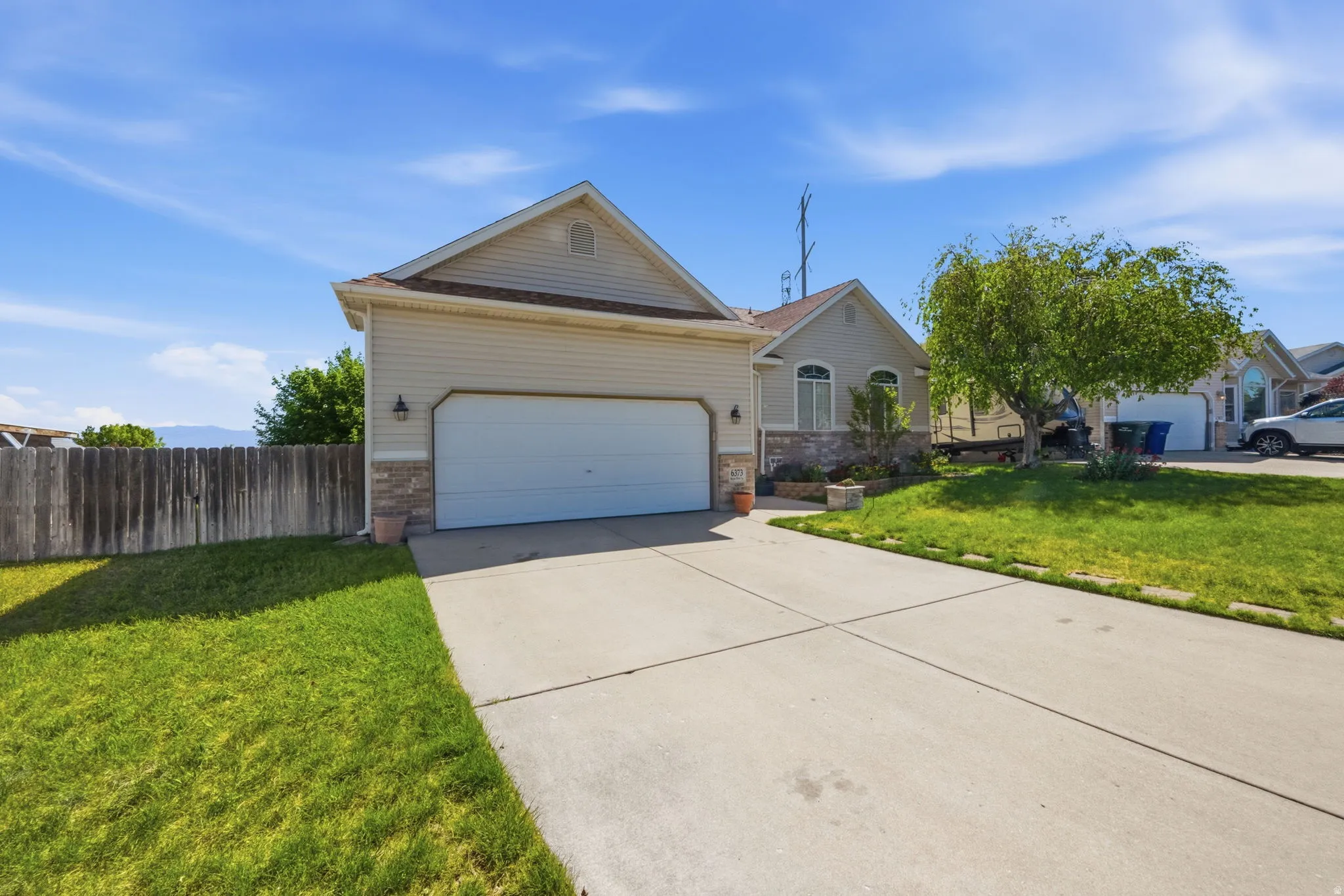 Front exterior featuring a two-car garage, concrete driveway, and neutral siding with stone accents