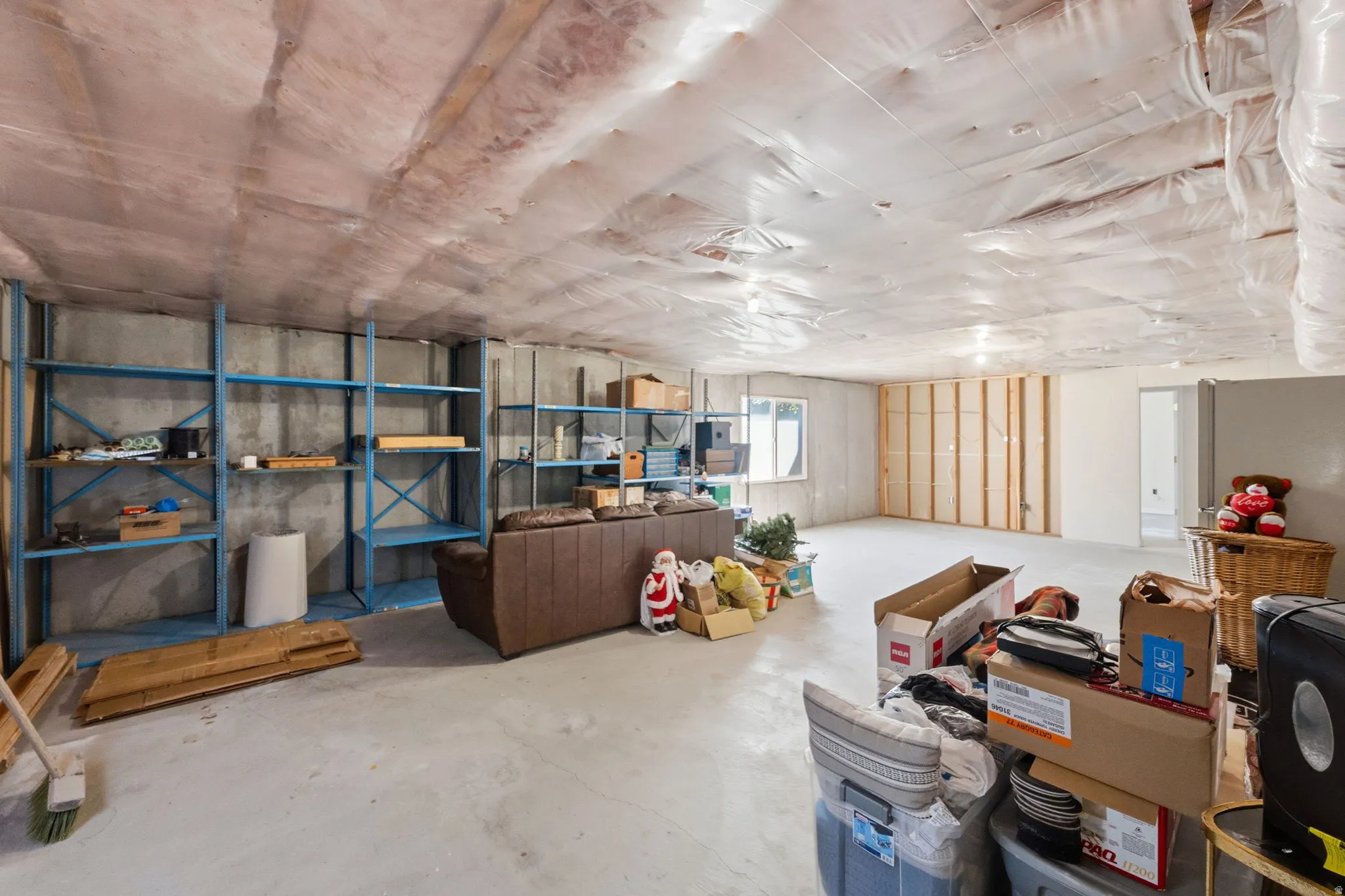 Unfinished basement with concrete flooring and exposed ceiling insulation