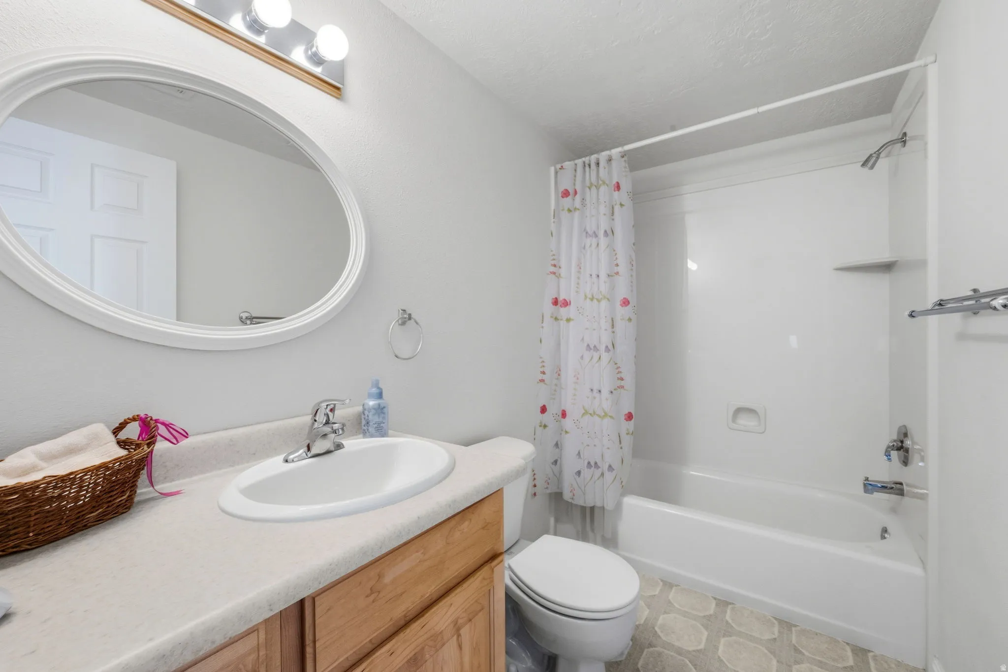 Bathroom featuring a single vanity with wood-finish cabinetry, a white oval sink, and a chrome faucet