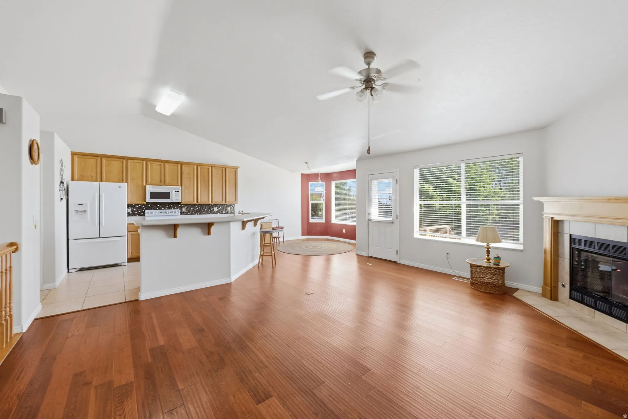 Spacious living area featuring wood-finish flooring, a corner fireplace with a tiled surround, and expansive windows