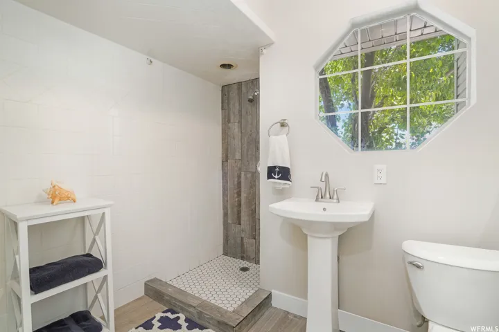 Bathroom featuring a pedestal sink, a toilet, and an octagonal window