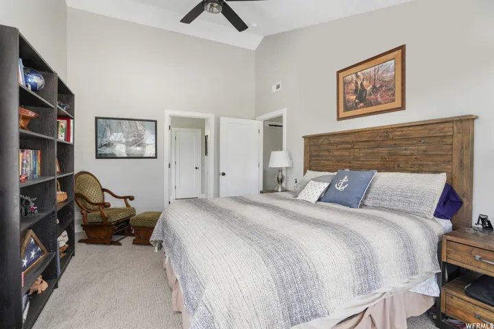 Vaulted ceiling bedroom with a wood-plank headboard and light-toned carpeting