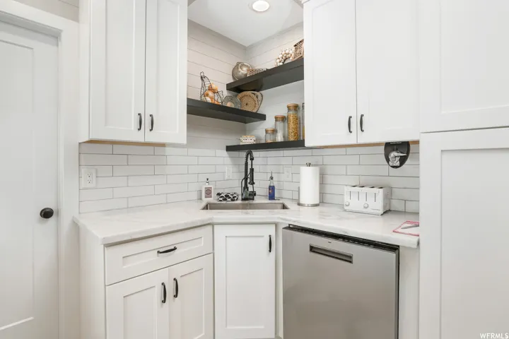 White shaker cabinetry with dark hardware, stone countertops, and a subway tile backsplash