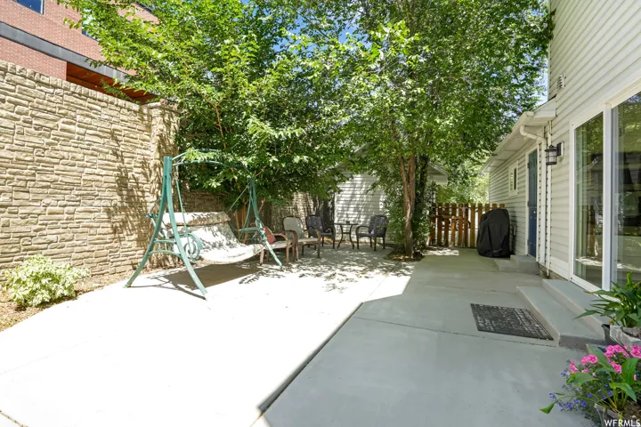 Private patio area featuring a textured stone privacy wall and mature trees