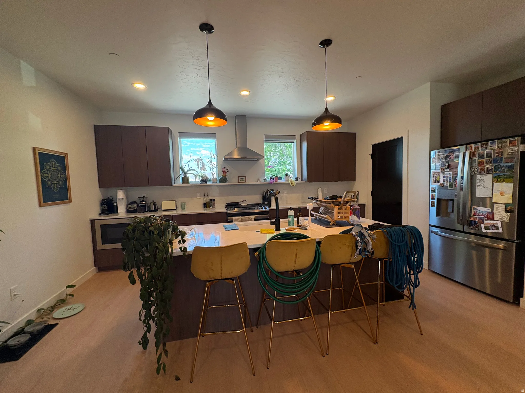 Modern kitchen featuring an island with built-in sink, stainless steel appliances, dark wood-finish cabinetry, and recessed lighting