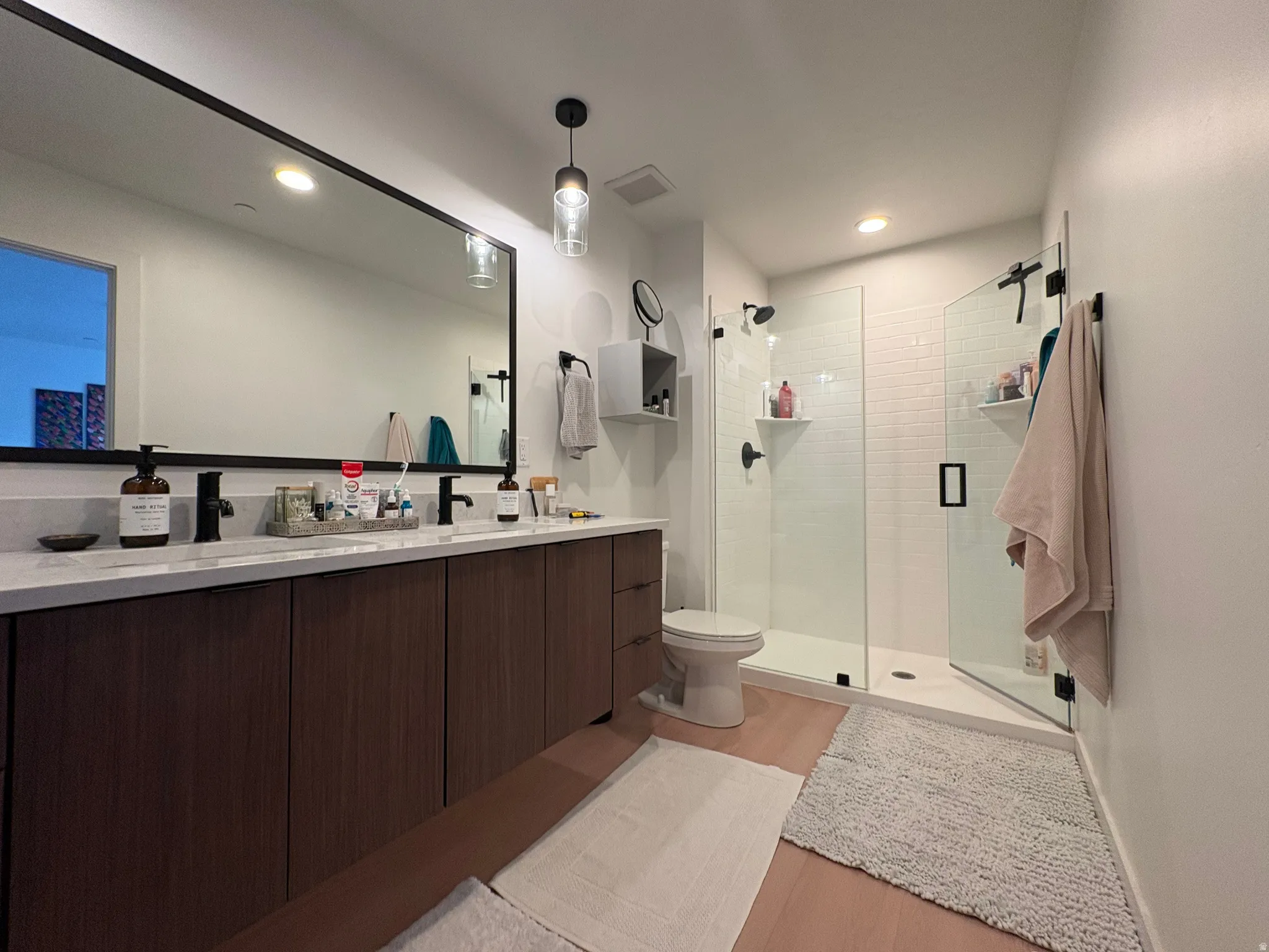 Contemporary bath featuring a double vanity with dark wood-finish cabinetry and a light-toned countertop